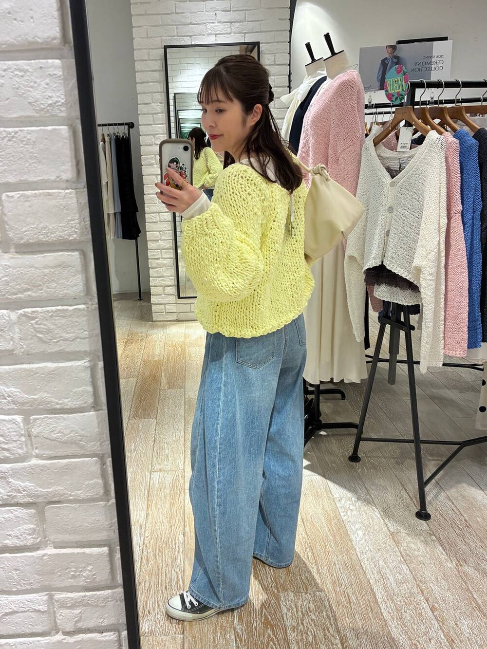 ブルー系のデニムパンツ、イエロー系のニット/セーター、ホワイト系のTシャツ/カットソーを着用したレディースの冬コーディネートの4枚目の写真