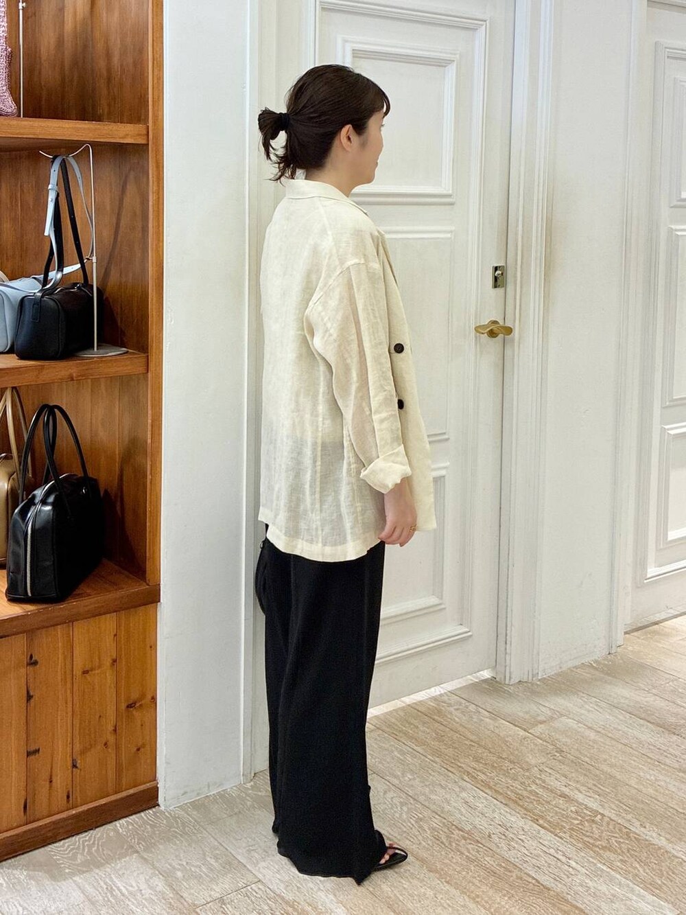 ブラック系のハンドバッグ、ブラック系のサンダル、ベージュ系のテーラードジャケットを着用したレディースの夏コーディネートの2枚目の写真