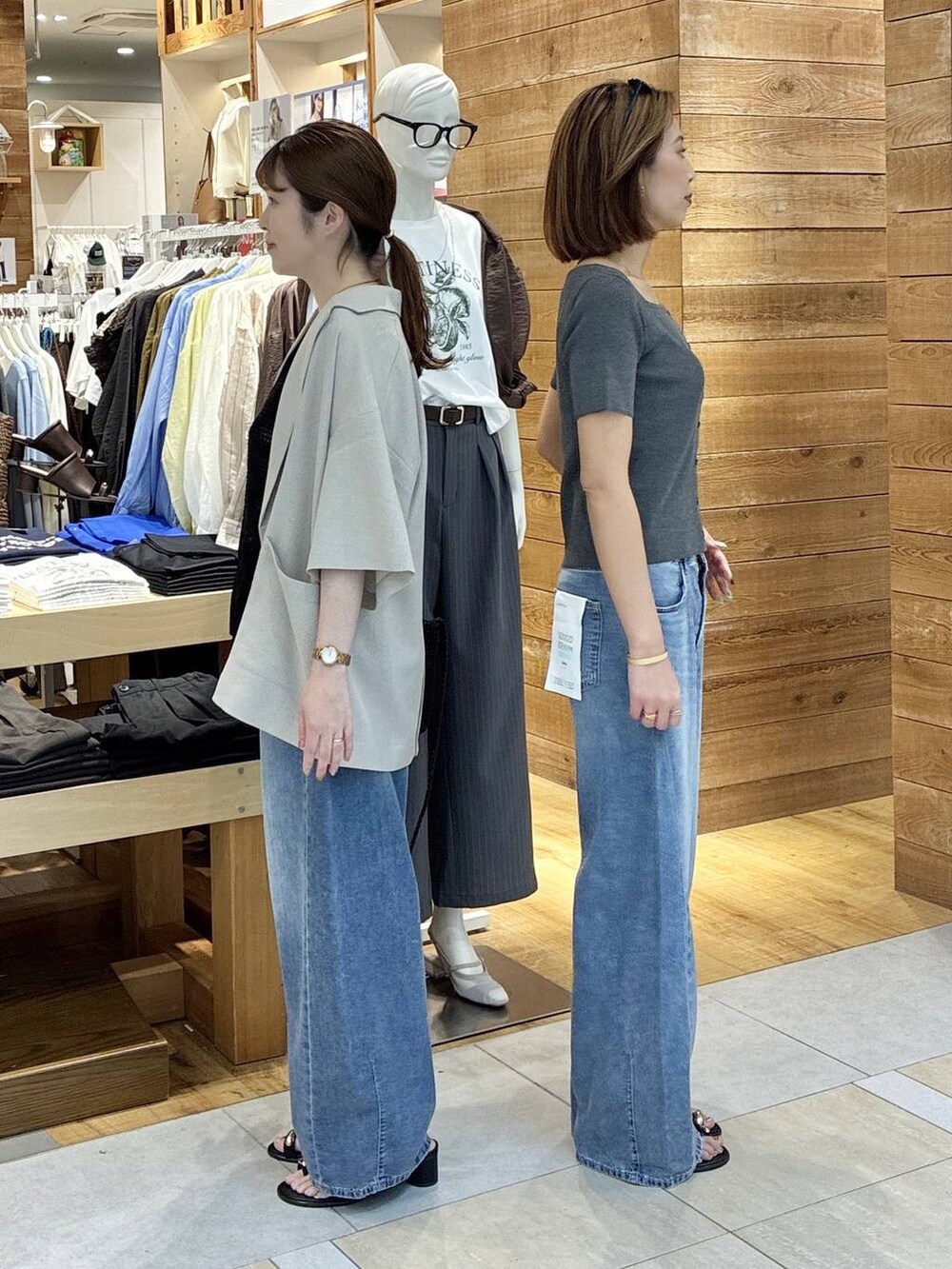ブルー系のデニムパンツ、ベージュ系のテーラードジャケット、ブラック系のサンダルを着用したレディースの春コーディネートの2枚目の写真