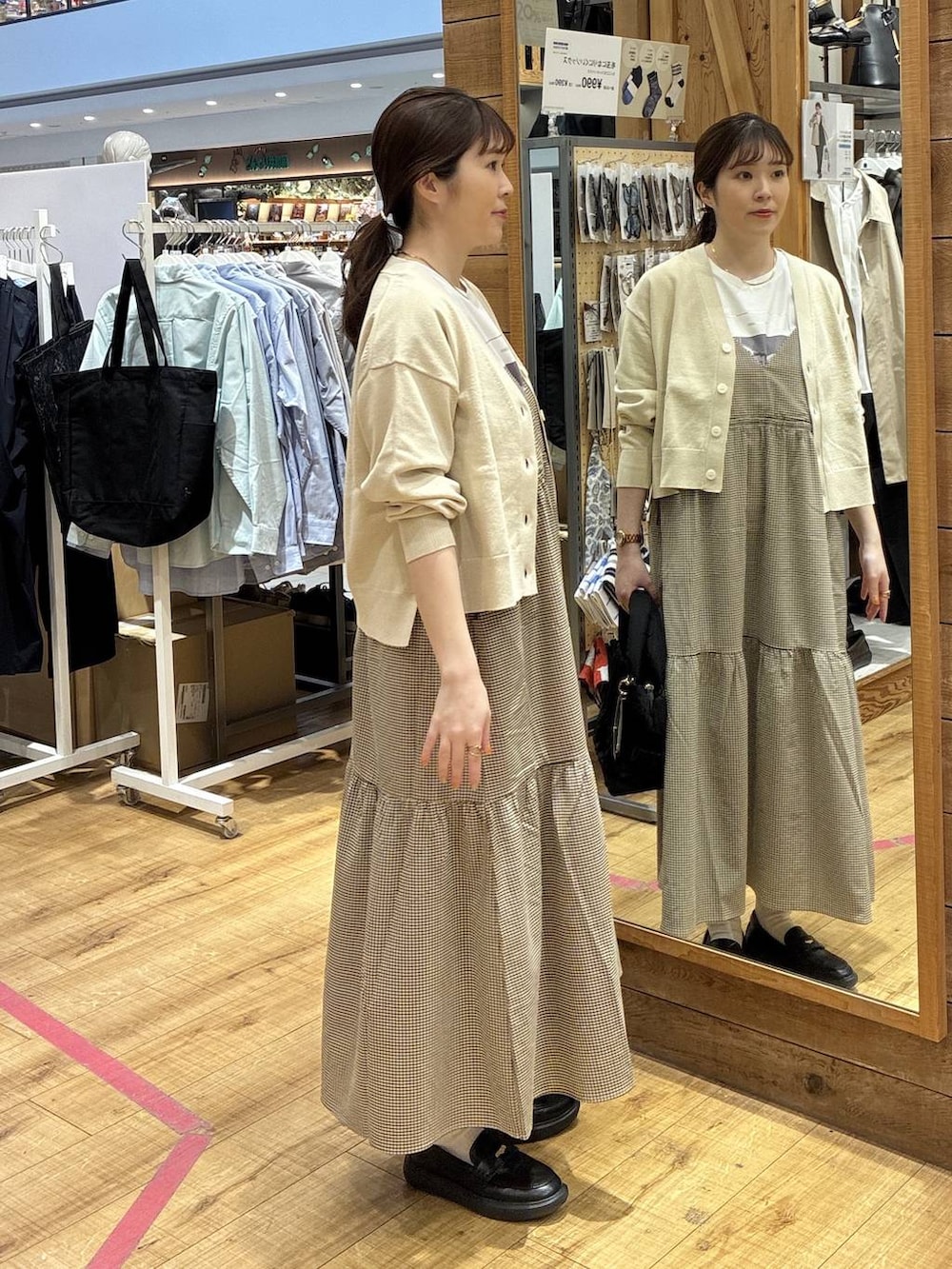 ブラック系のトートバッグ、ベージュ系のカーディガン/ボレロ、イエロー系のワンピースを着用したレディースの春コーディネートの2枚目の写真