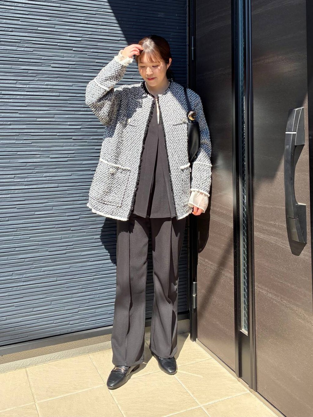 ブラック系のローファー、ブラック系のショルダーバッグ、ブラック系のノーカラージャケットを着用したレディースの春コーディネートの4枚目の写真