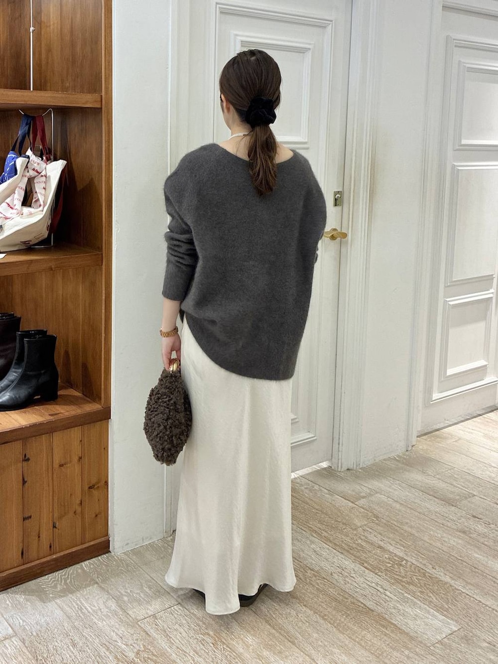 グレー系のニット/セーター、ホワイト系のスカート、ブラウン系のハンドバッグを着用したレディースの秋コーディネートの4枚目の写真