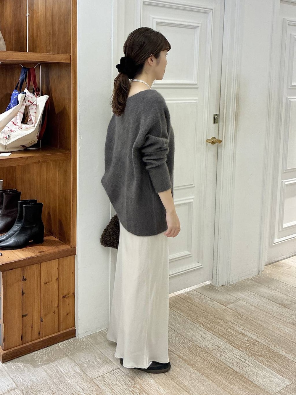 グレー系のニット/セーター、ホワイト系のスカート、ブラウン系のハンドバッグを着用したレディースの秋コーディネートの3枚目の写真