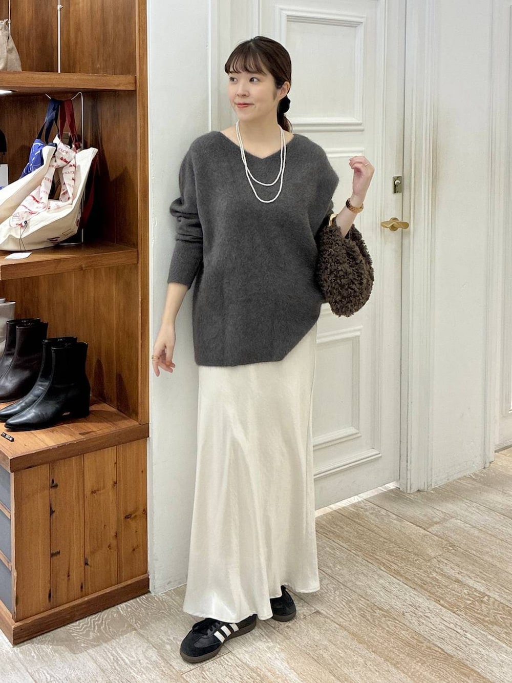 グレー系のニット/セーター、ホワイト系のスカート、ブラウン系のハンドバッグを着用したレディースの秋コーディネートの2枚目の写真