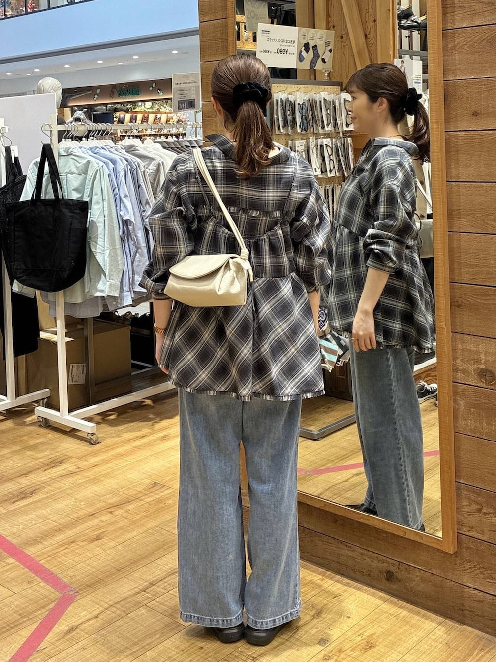 ブルー系のデニムパンツ、ベージュ系のショルダーバッグ、ブラック系のシャツ/ブラウスを着用したレディースの春コーディネートの3枚目の写真