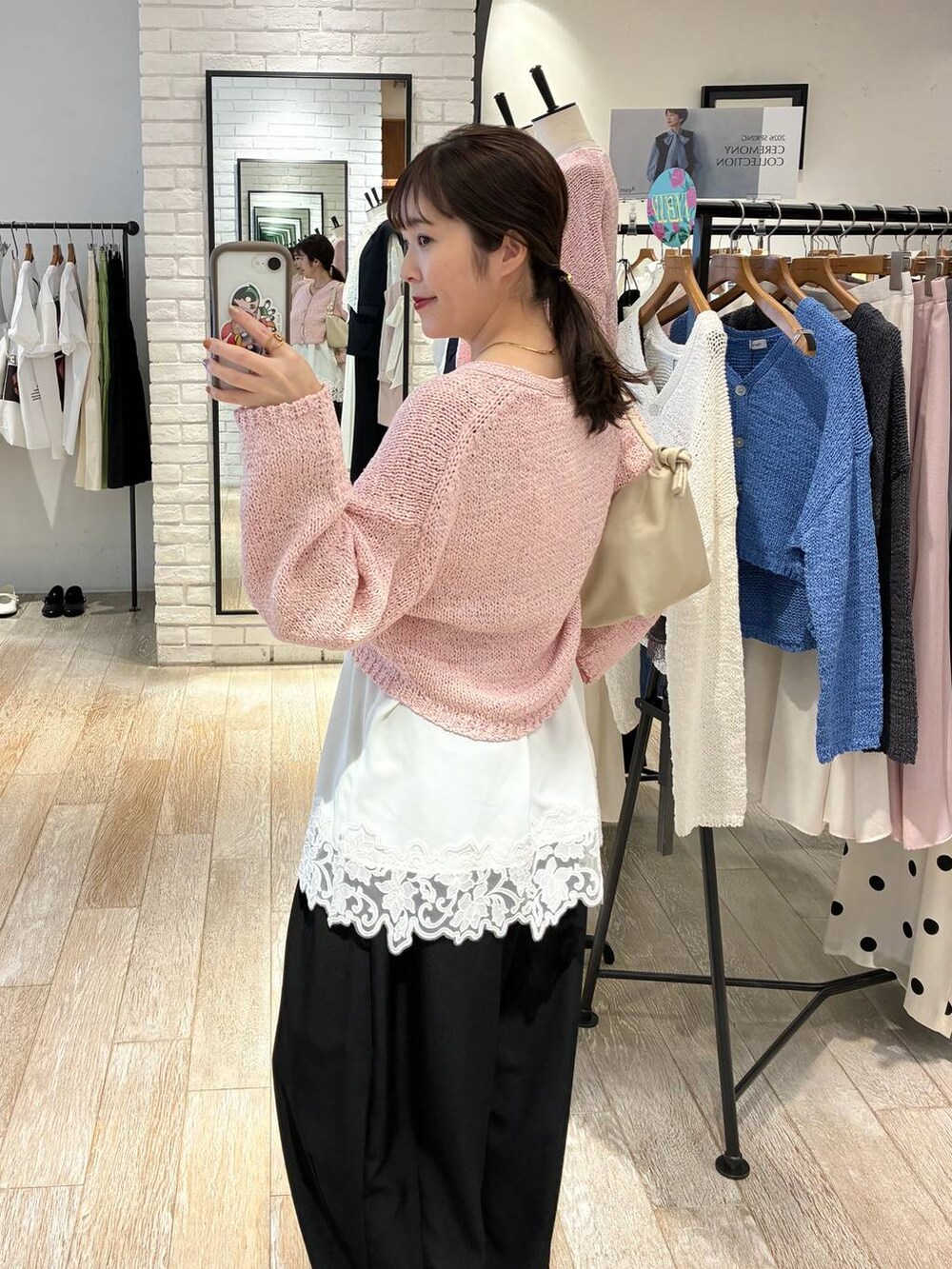 ブラック系のスラックス、ホワイト系のキャミソール、ピンク系のカーディガン/ボレロを着用したレディースの冬コーディネートの2枚目の写真