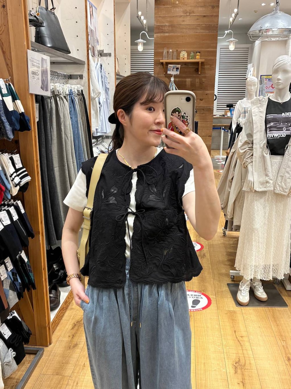 ブラック系のベスト、ブルー系のデニムパンツを着用したレディースの春コーディネートの3枚目の写真