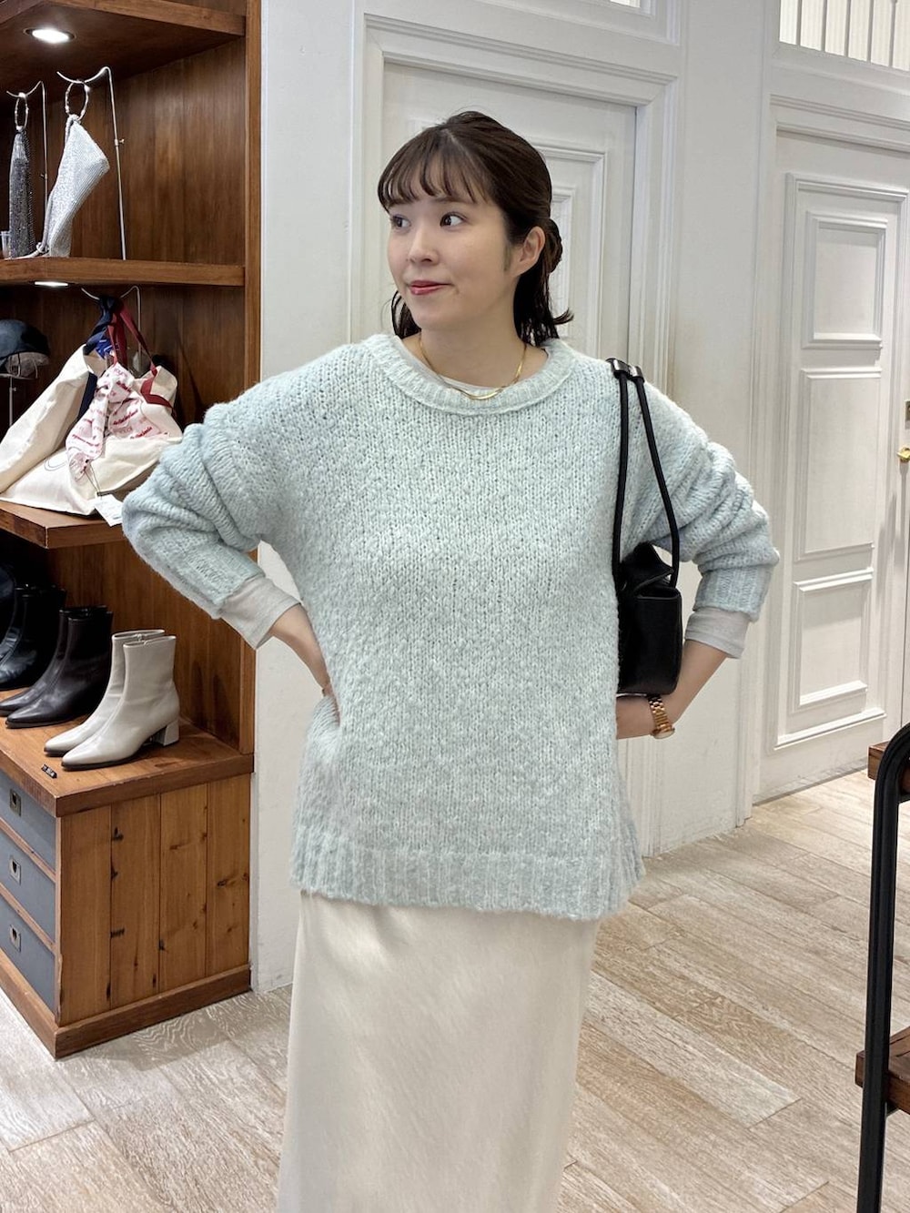 ホワイト系のスカート、グリーン系のニット/セーター、ブラック系のショルダーバッグを着用したレディースの冬コーディネートの4枚目の写真