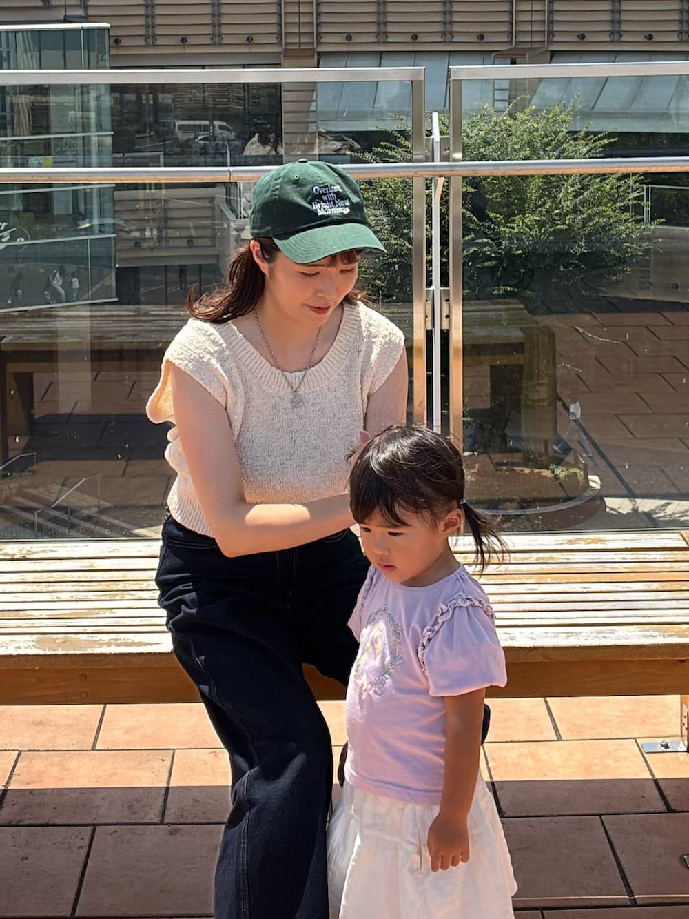 ベージュ系のニット/セーター、グリーン系のキャップを着用したレディースの夏コーディネートの2枚目の写真