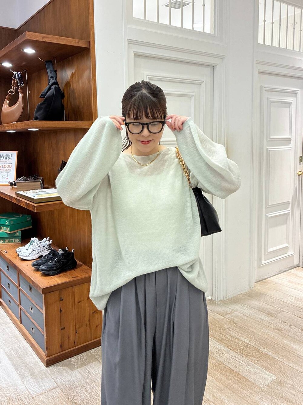 グリーン系のニット/セーター、グレー系のスラックス、ブラック系のショルダーバッグを着用したレディースの秋コーディネートの4枚目の写真