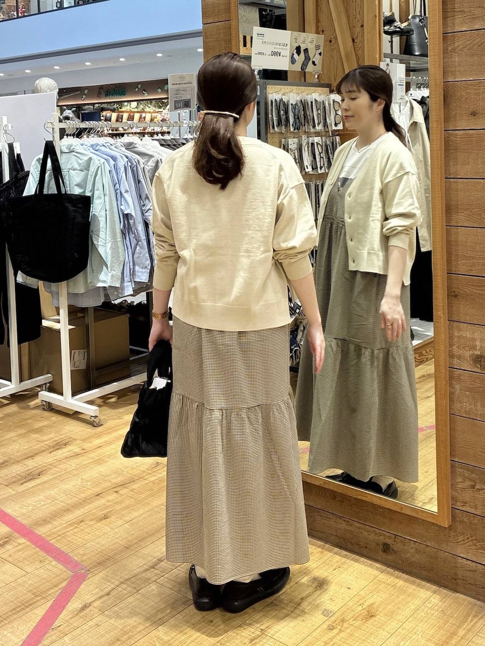 ブラック系のトートバッグ、ベージュ系のカーディガン/ボレロ、イエロー系のワンピースを着用したレディースの春コーディネートの3枚目の写真