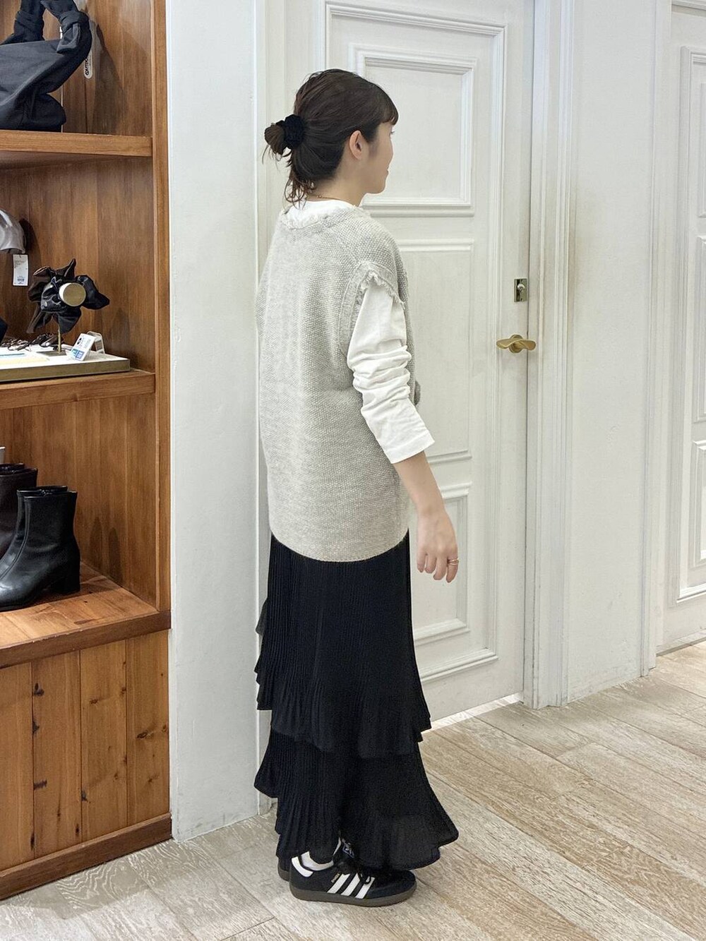 グレー系のベスト、ブラック系のスカート、ブラック系のショルダーバッグを着用したレディースの秋コーディネートの2枚目の写真