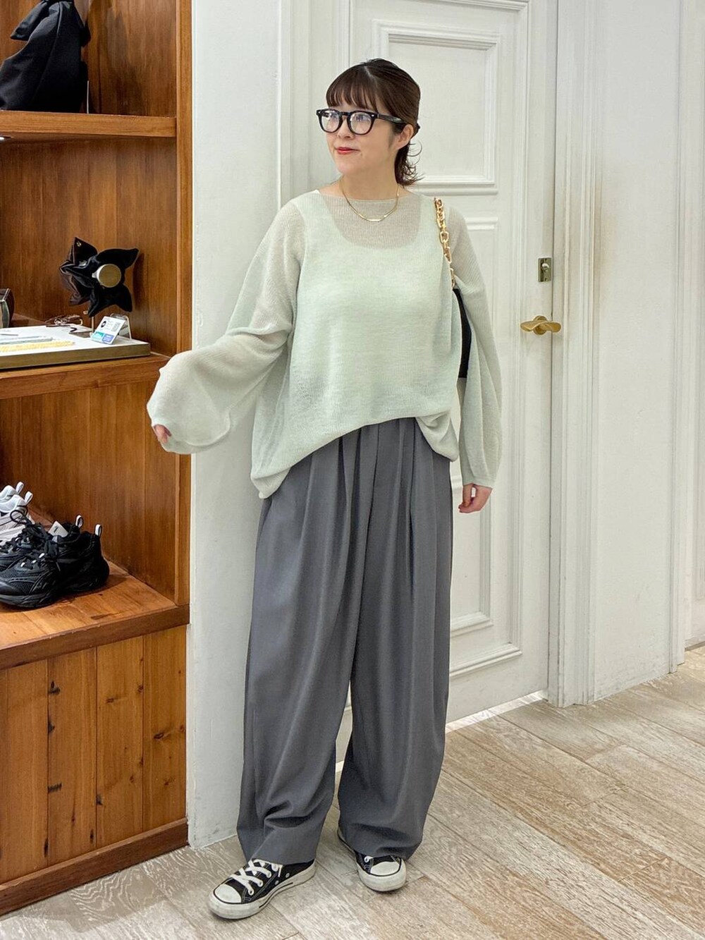 グリーン系のニット/セーター、グレー系のスラックス、ブラック系のショルダーバッグを着用したレディースの秋コーディネートの6枚目の写真