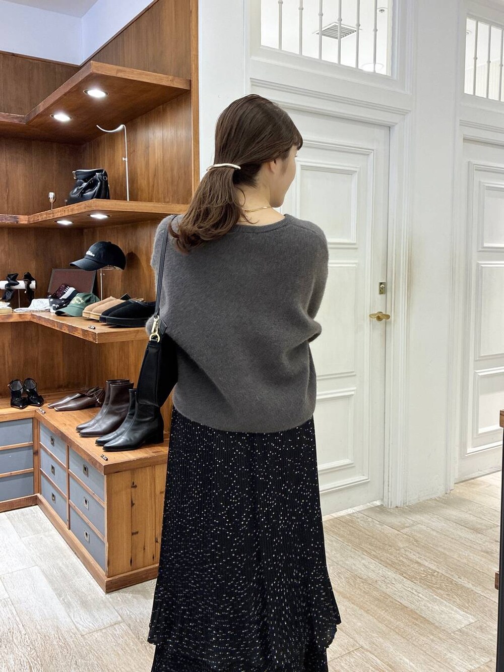 ベージュ系のブーツ、グレー系のスカート、ブラック系のショルダーバッグを着用したレディースの秋コーディネートの6枚目の写真