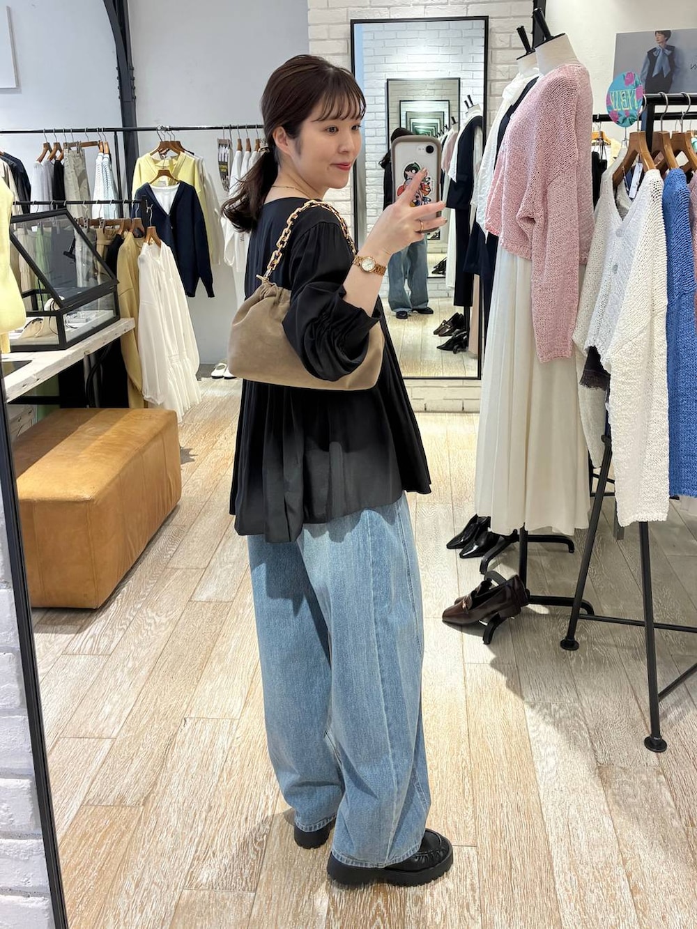 ブルー系のデニムパンツ、ベージュ系のショルダーバッグ、ブラック系のシャツ/ブラウスを着用したレディースの春コーディネートの2枚目の写真