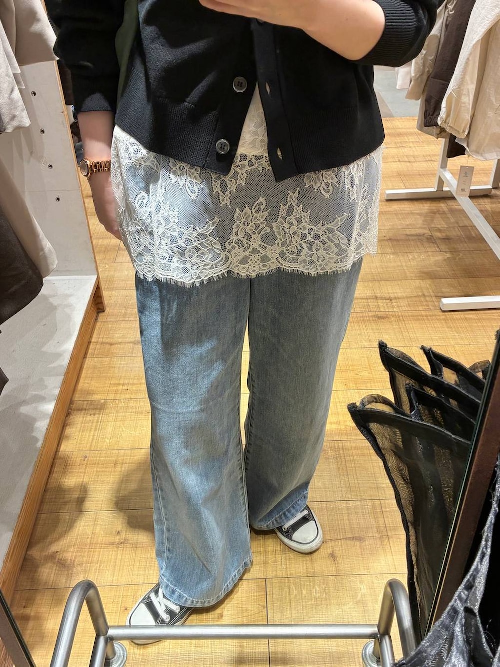 ブルー系のデニムパンツ、ブラック系のカーディガン/ボレロ、ホワイト系のキャミソールを着用したレディースの春コーディネートの2枚目の写真