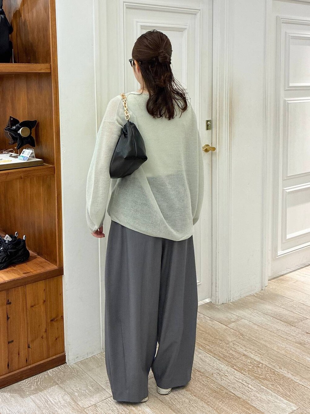 グリーン系のニット/セーター、グレー系のスラックス、ブラック系のショルダーバッグを着用したレディースの秋コーディネートの3枚目の写真