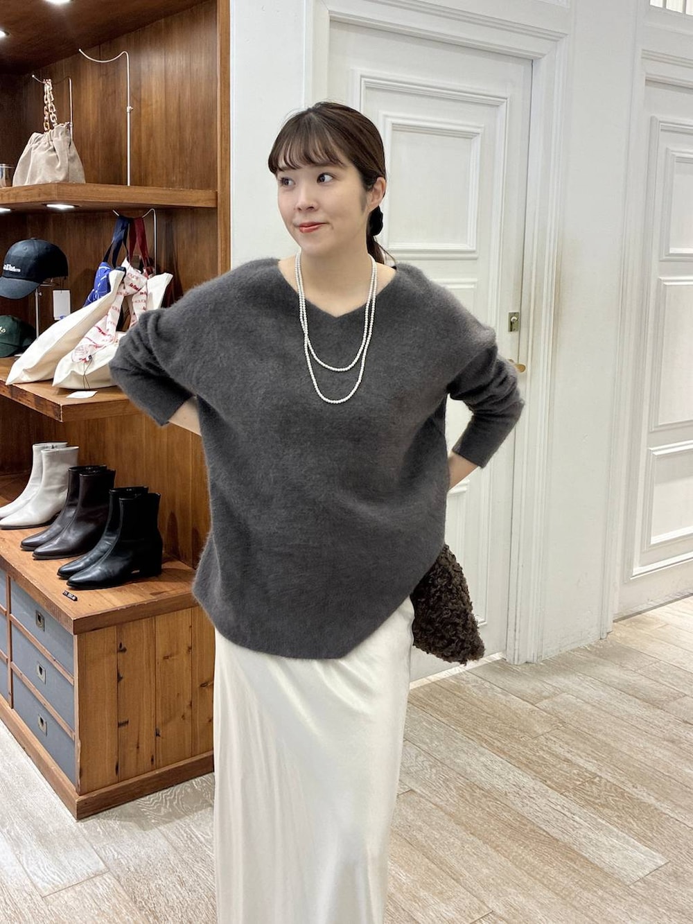 グレー系のニット/セーター、ホワイト系のスカート、ブラウン系のハンドバッグを着用したレディースの秋コーディネートの5枚目の写真