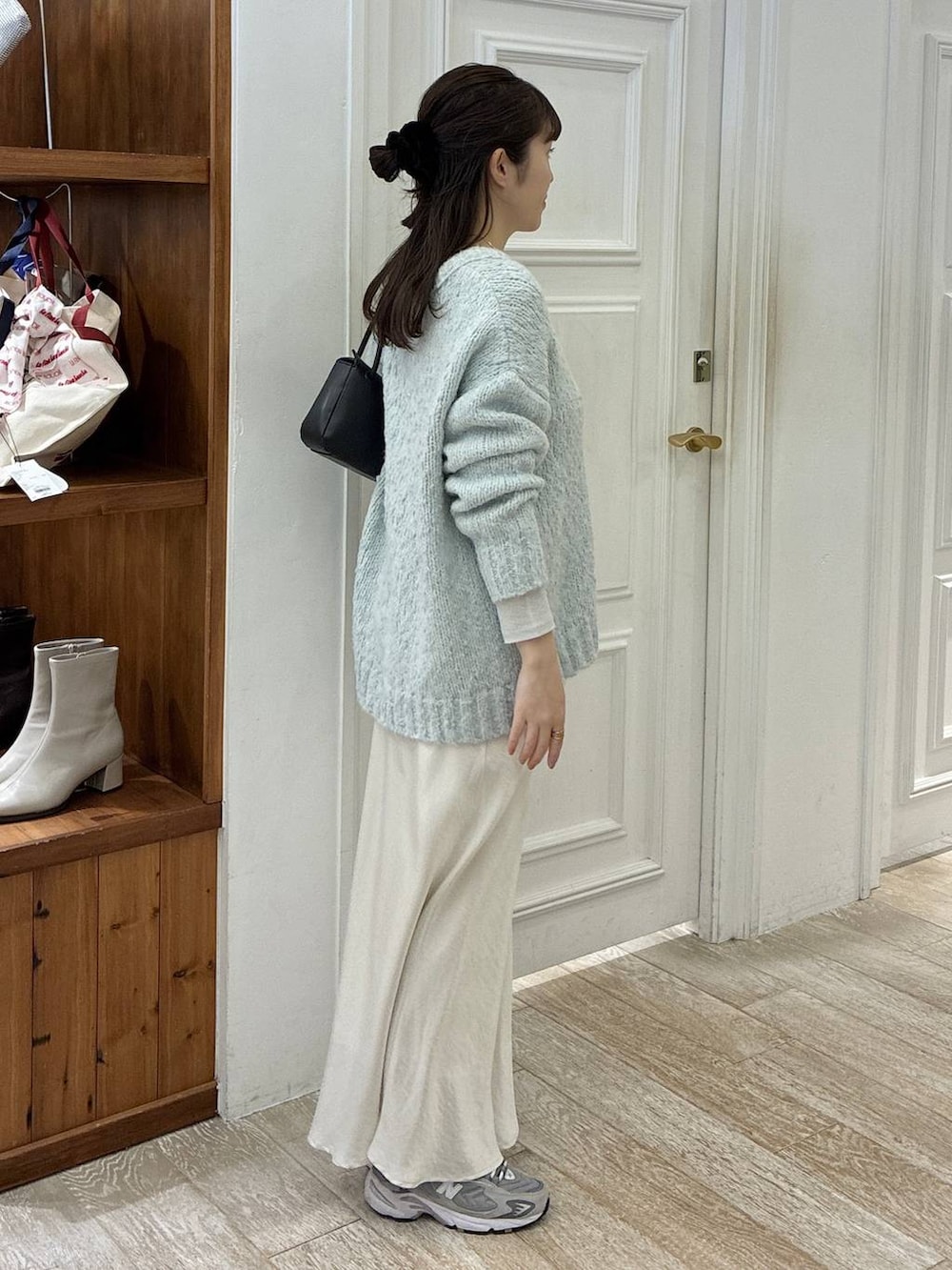 ホワイト系のスカート、グリーン系のニット/セーター、ブラック系のショルダーバッグを着用したレディースの冬コーディネートの2枚目の写真