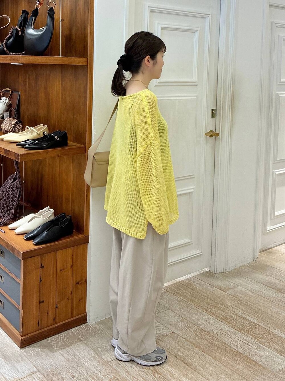 ブラウン系のショルダーバッグ、グレー系のその他パンツ、イエロー系のニット/セーターを着用したレディースの春コーディネートの2枚目の写真