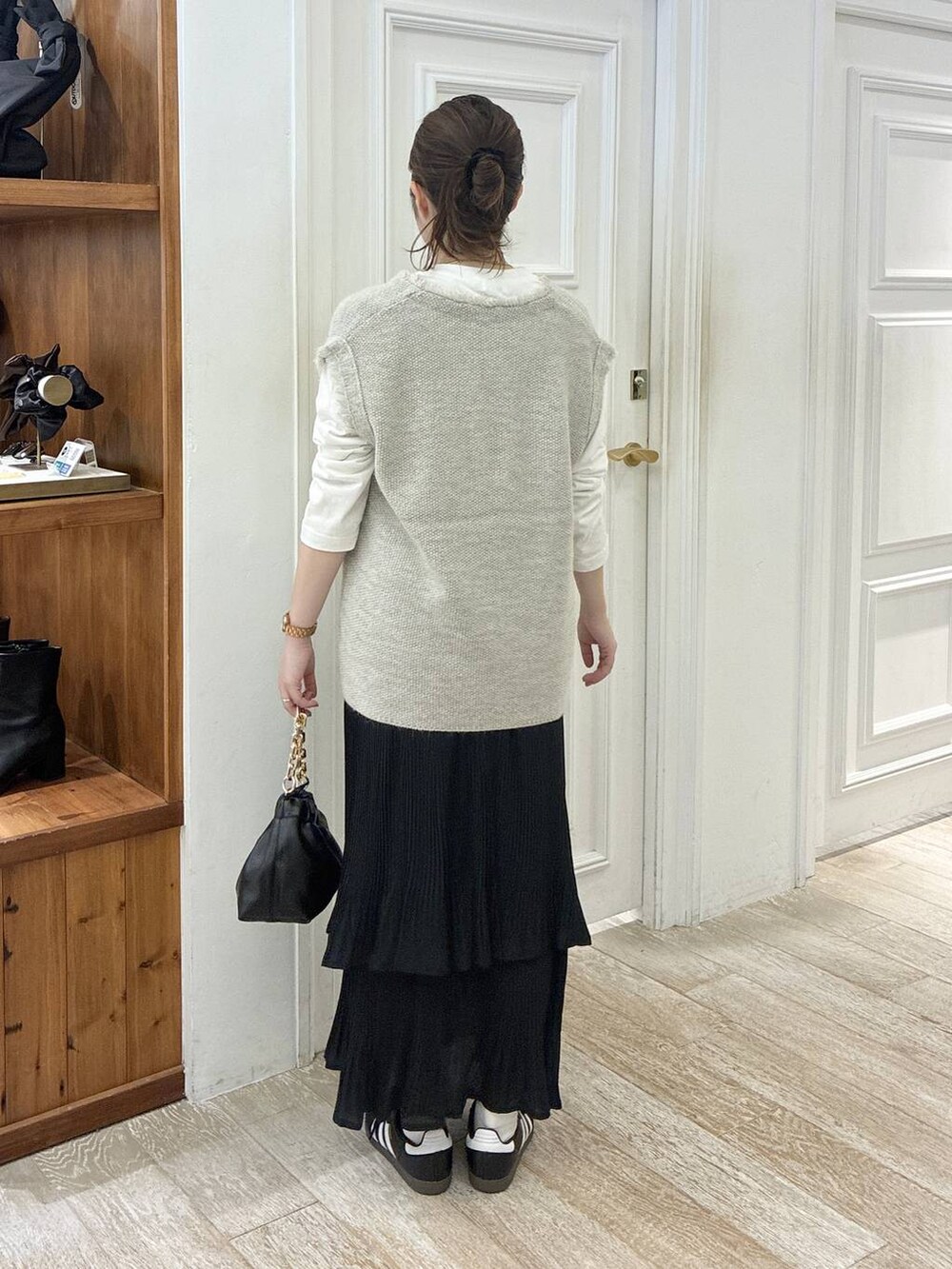 グレー系のベスト、ブラック系のスカート、ブラック系のショルダーバッグを着用したレディースの秋コーディネートの3枚目の写真