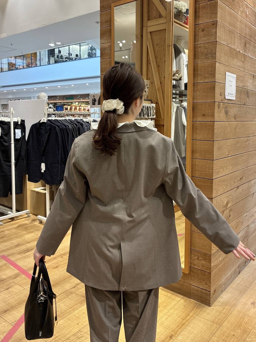 ブラック系のショルダーバッグ、ブラウン系のスラックス、ブラウン系のテーラードジャケットを着用したレディースの春コーディネートの6枚目の写真