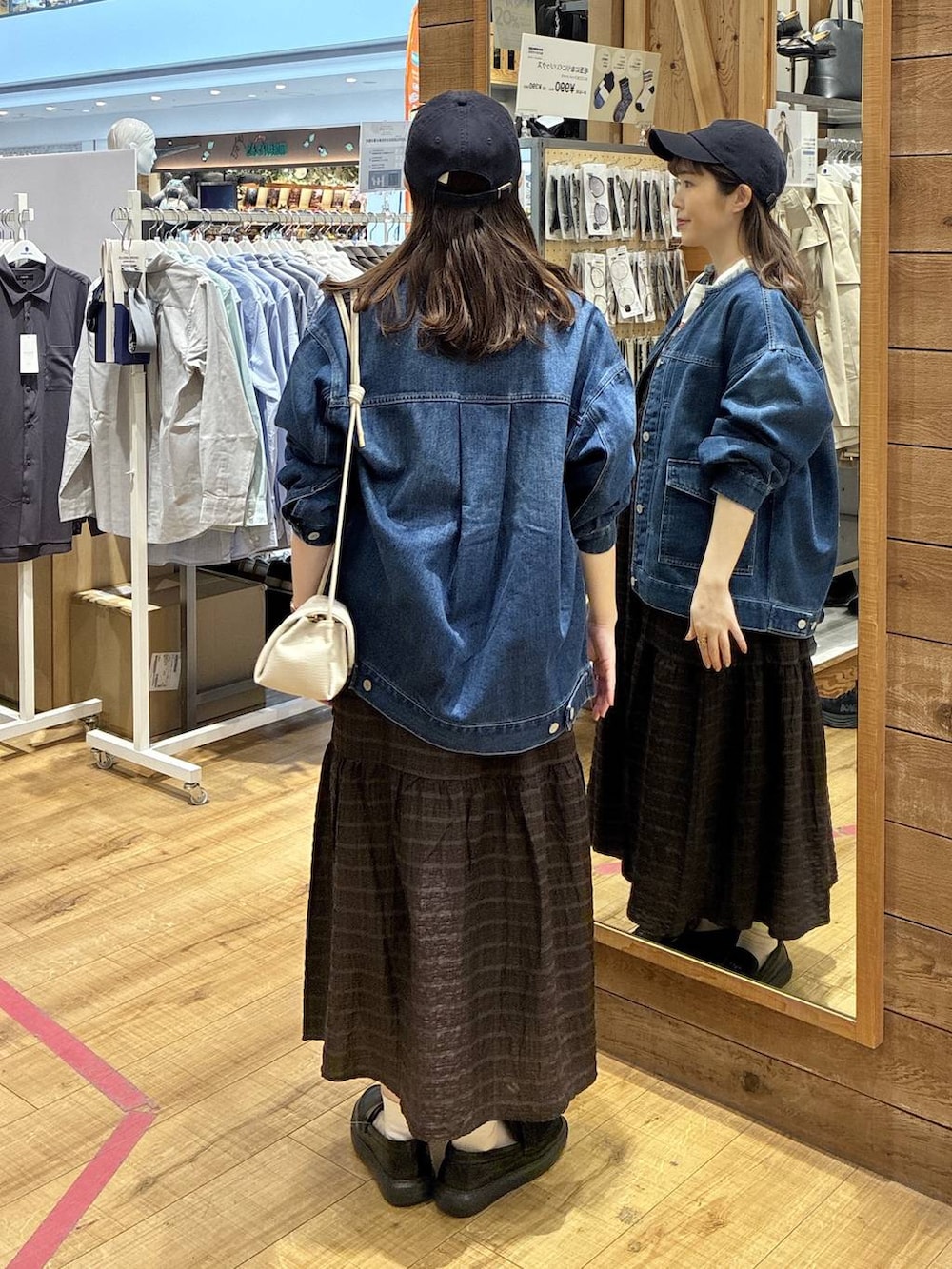 ベージュ系のショルダーバッグ、ブルー系のデニムジャケット、ブラウン系のワンピースを着用したレディースの春コーディネートの3枚目の写真