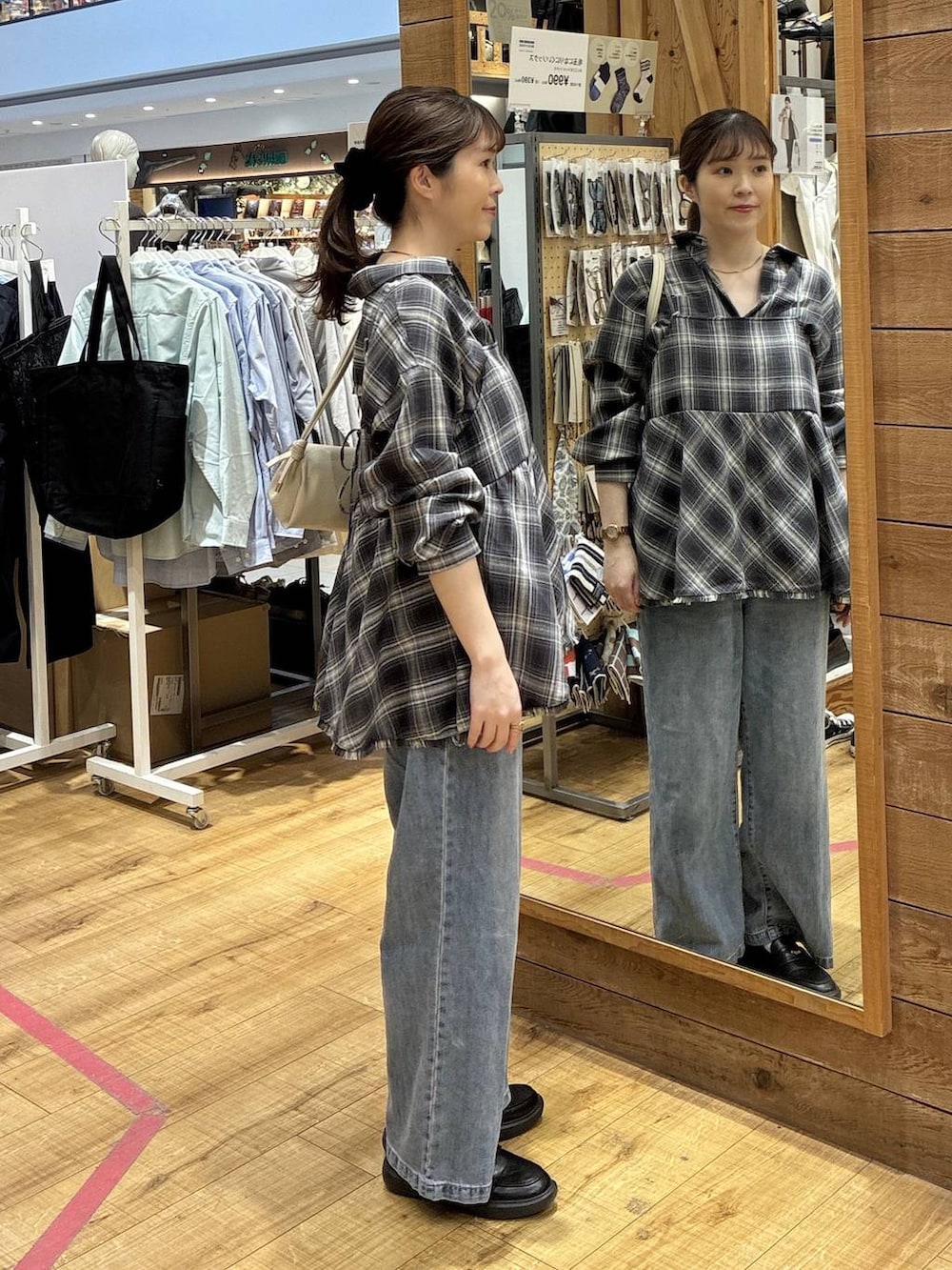 ブルー系のデニムパンツ、ベージュ系のショルダーバッグ、ブラック系のシャツ/ブラウスを着用したレディースの春コーディネートの2枚目の写真