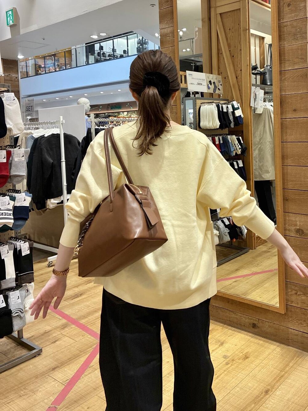 ブラウン系のボストンバッグ、ブルー系のデニムパンツ、イエロー系のカーディガン/ボレロを着用したレディースの春コーディネートの5枚目の写真