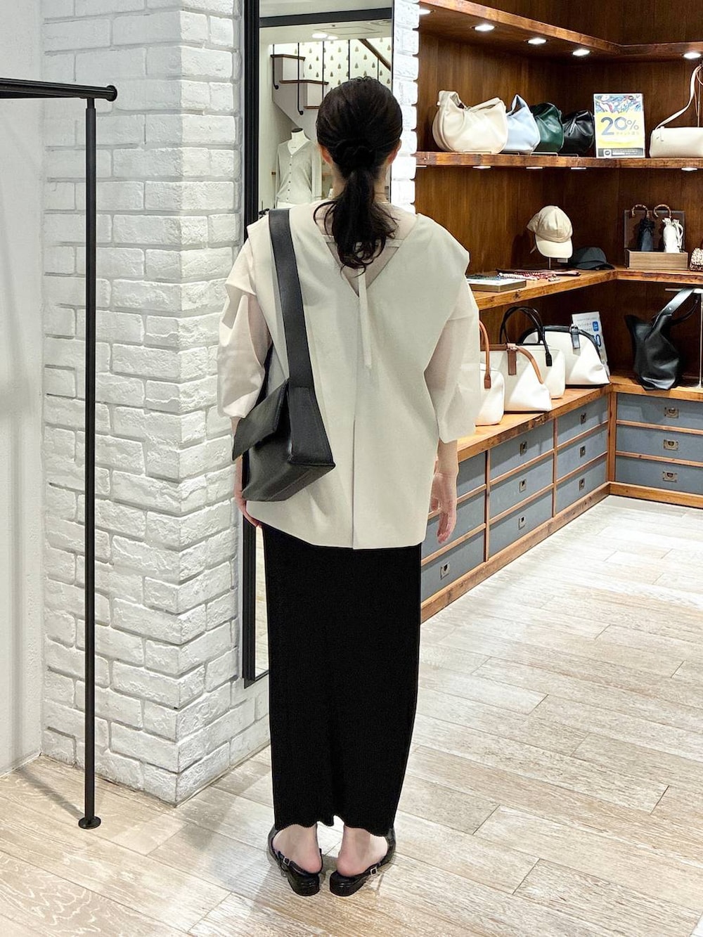 ベージュ系のパンツドレス、ブラック系のスカート、ホワイト系のシャツ/ブラウスを着用したレディースの春コーディネートの3枚目の写真
