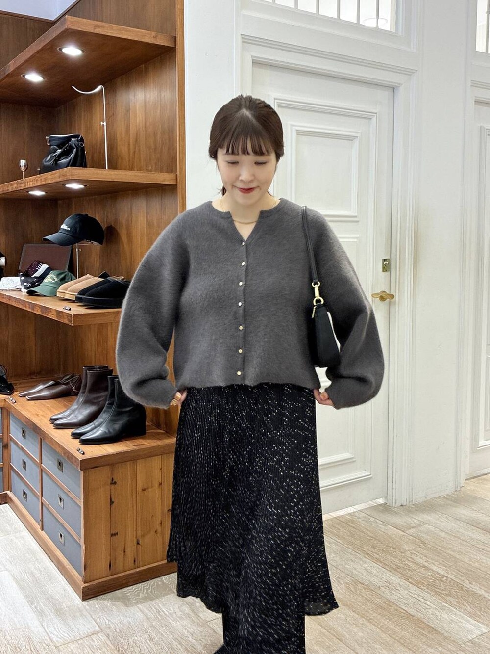 ベージュ系のブーツ、グレー系のスカート、ブラック系のショルダーバッグを着用したレディースの秋コーディネートの4枚目の写真