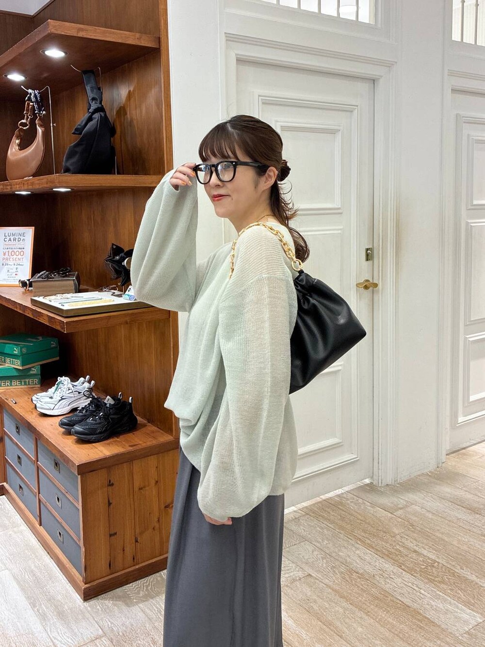 グリーン系のニット/セーター、グレー系のスラックス、ブラック系のショルダーバッグを着用したレディースの秋コーディネートの5枚目の写真