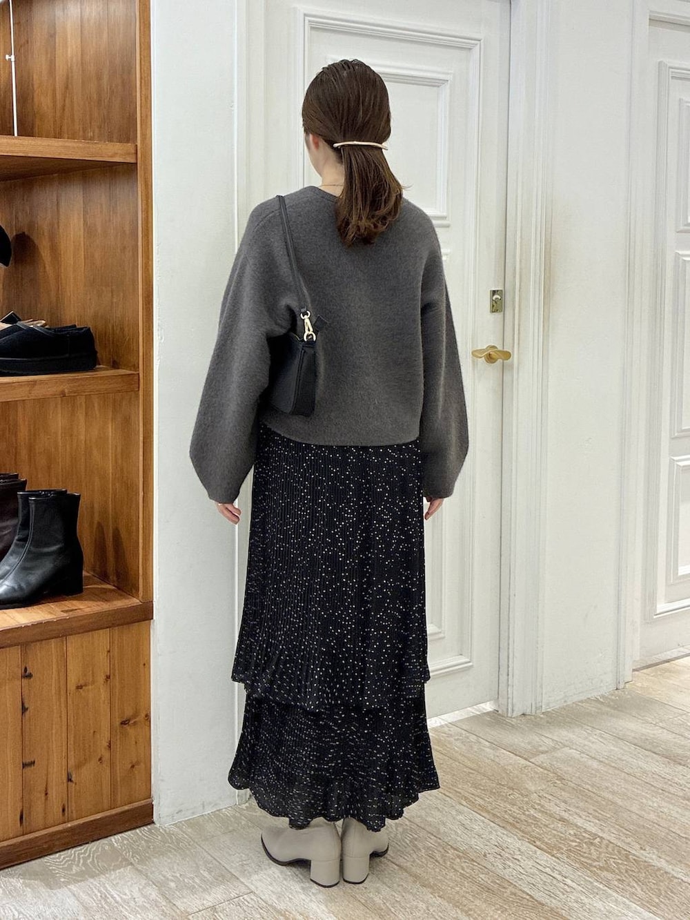 ベージュ系のブーツ、グレー系のスカート、ブラック系のショルダーバッグを着用したレディースの秋コーディネートの3枚目の写真