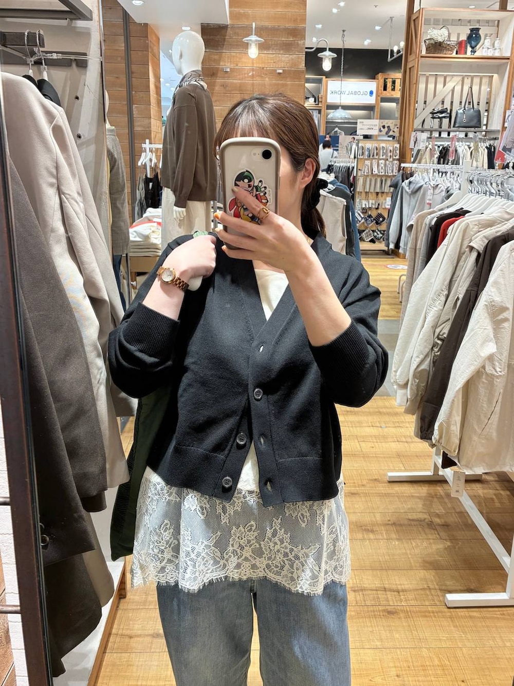 ブルー系のデニムパンツ、ブラック系のカーディガン/ボレロ、ホワイト系のキャミソールを着用したレディースの春コーディネートの3枚目の写真