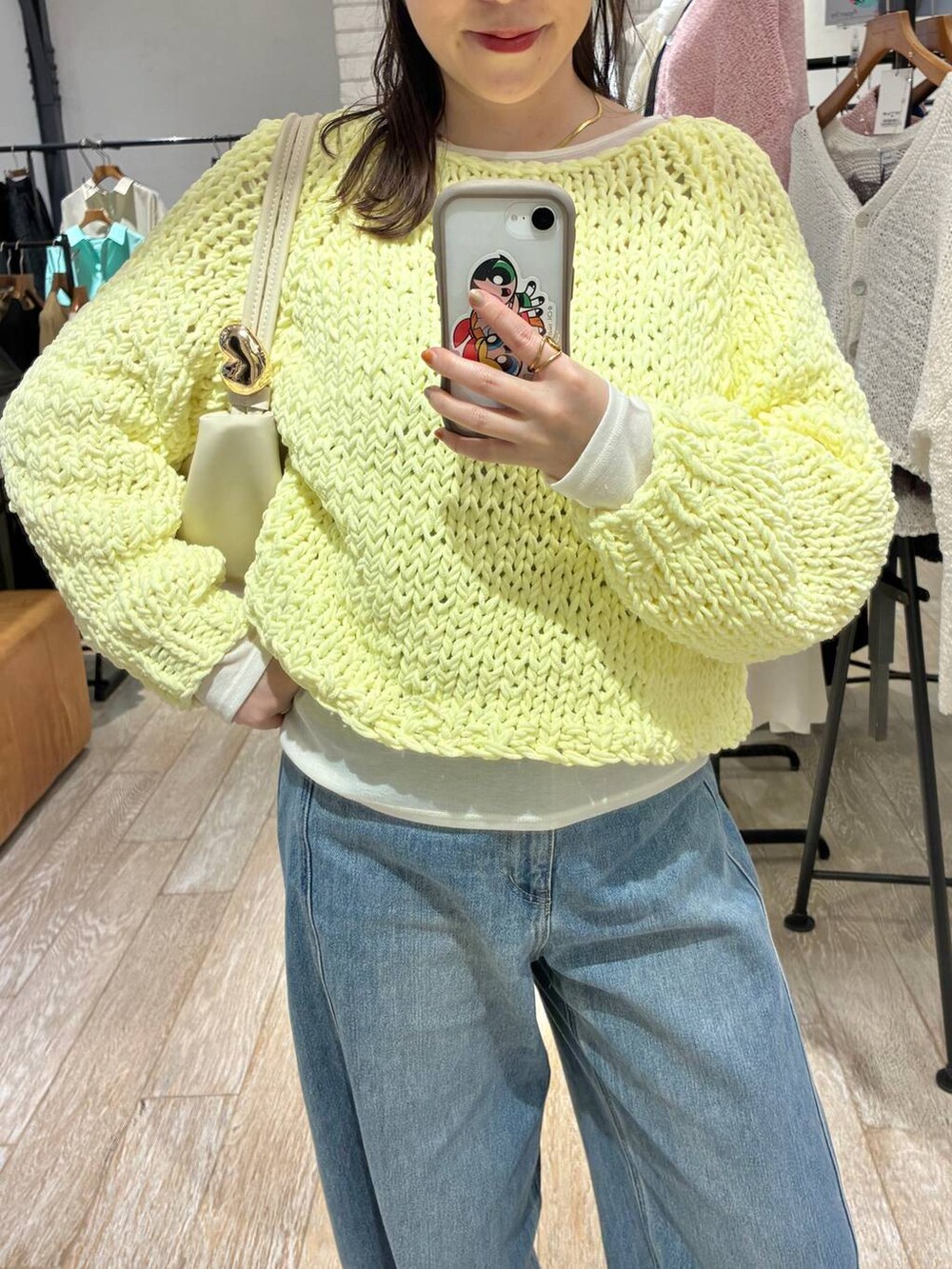 ブルー系のデニムパンツ、イエロー系のニット/セーター、ホワイト系のTシャツ/カットソーを着用したレディースの冬コーディネートの2枚目の写真