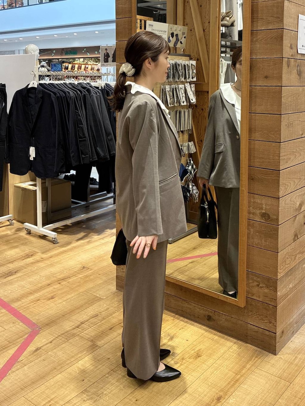 ブラック系のショルダーバッグ、ブラウン系のスラックス、ブラウン系のテーラードジャケットを着用したレディースの春コーディネートの3枚目の写真