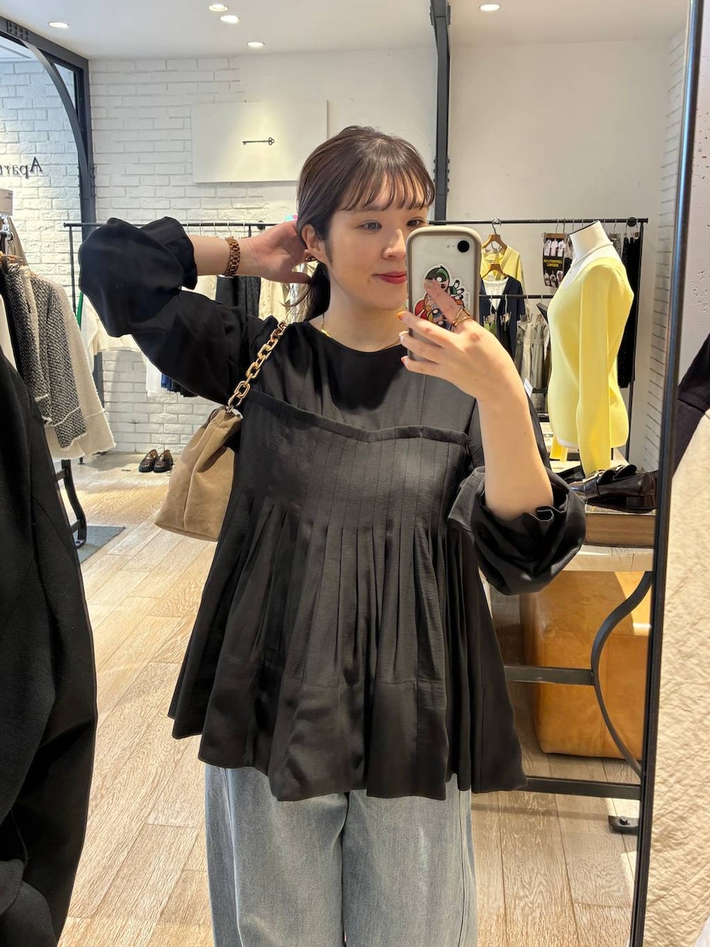 ブルー系のデニムパンツ、ベージュ系のショルダーバッグ、ブラック系のシャツ/ブラウスを着用したレディースの春コーディネートの3枚目の写真