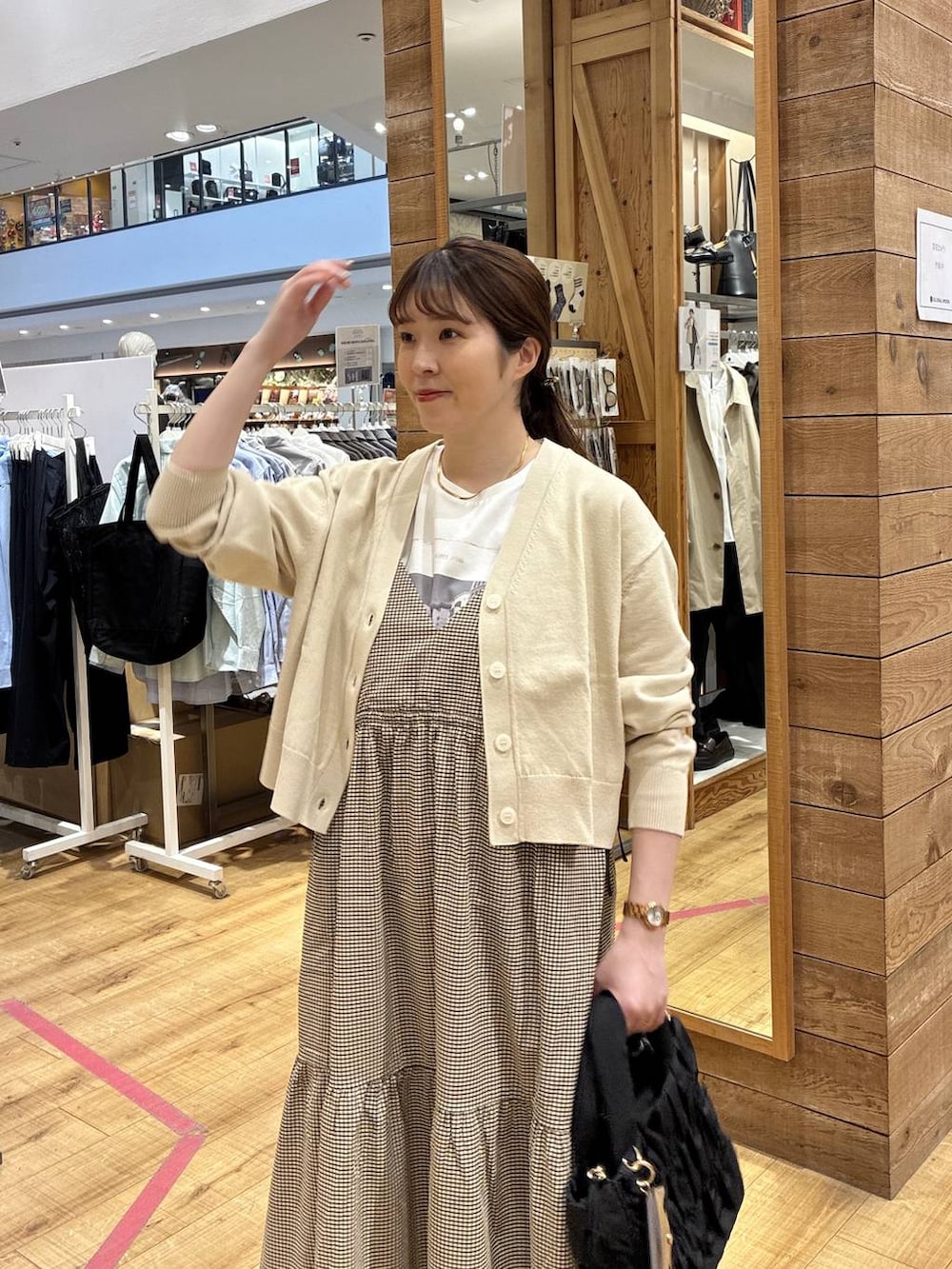 ブラック系のトートバッグ、ベージュ系のカーディガン/ボレロ、イエロー系のワンピースを着用したレディースの春コーディネートの4枚目の写真