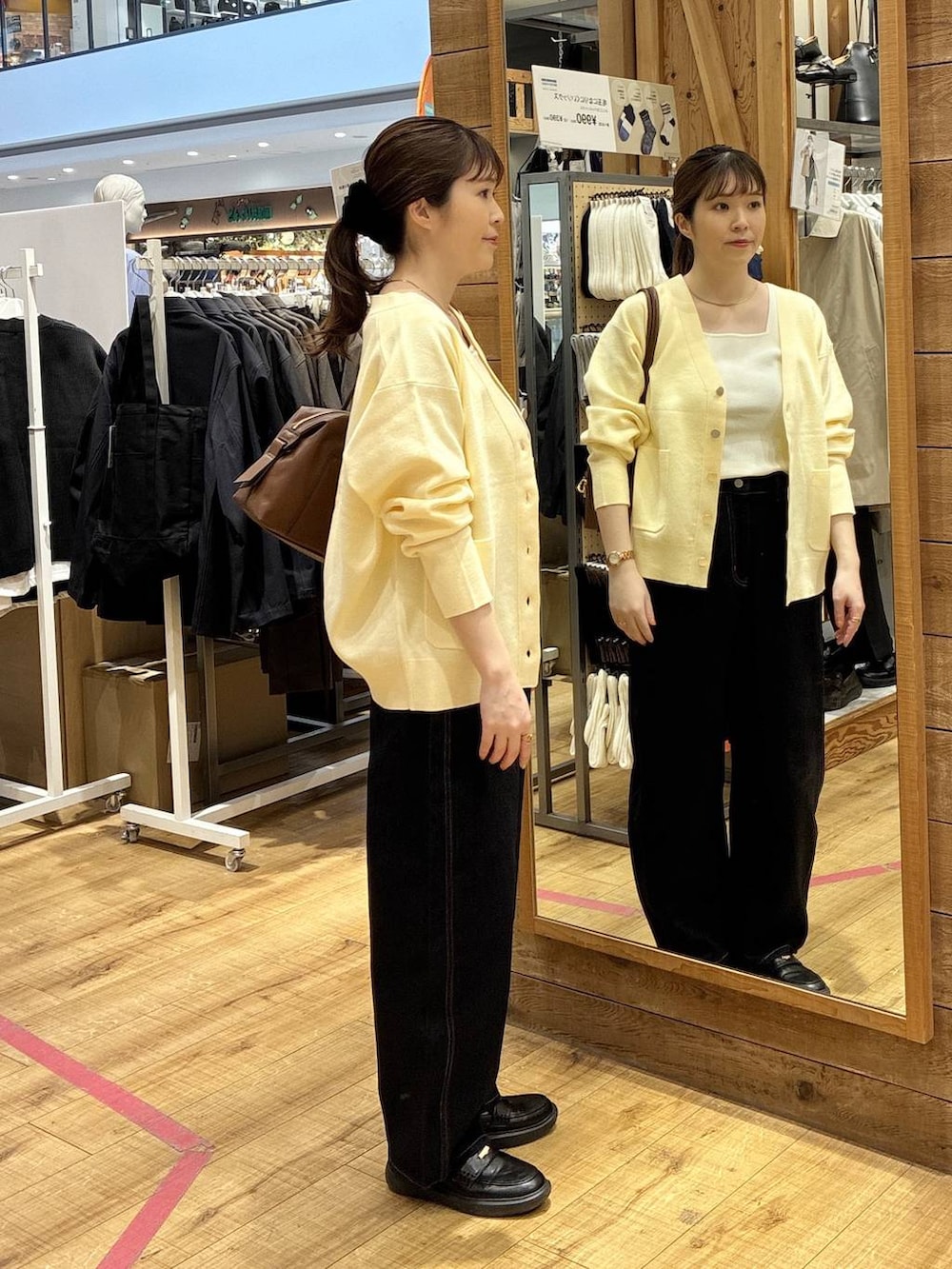 ブラウン系のボストンバッグ、ブルー系のデニムパンツ、イエロー系のカーディガン/ボレロを着用したレディースの春コーディネートの2枚目の写真