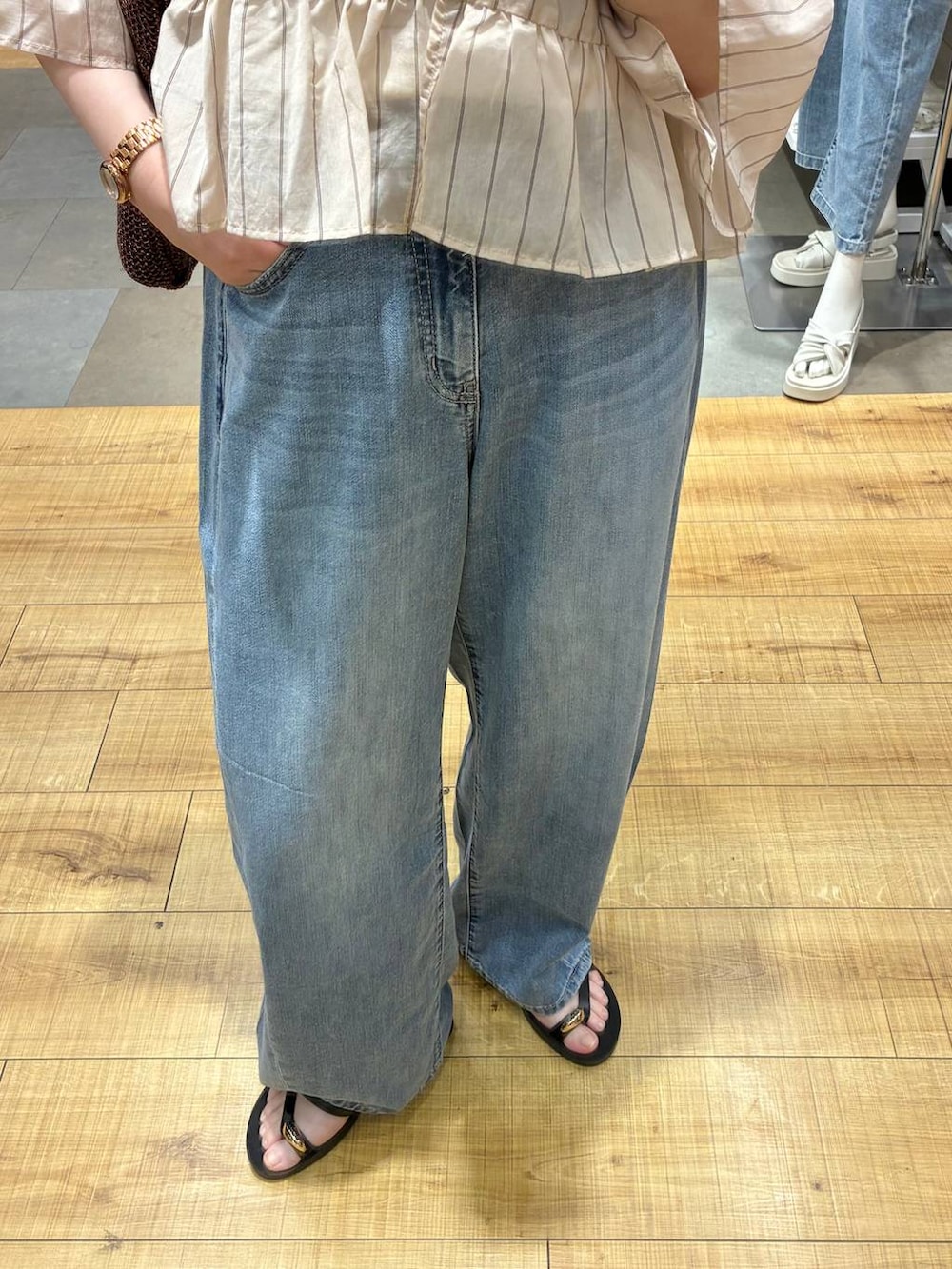 ブルー系のデニムパンツ、ホワイト系のタンクトップ、ブラウン系のトートバッグを着用したレディースの夏コーディネートの3枚目の写真