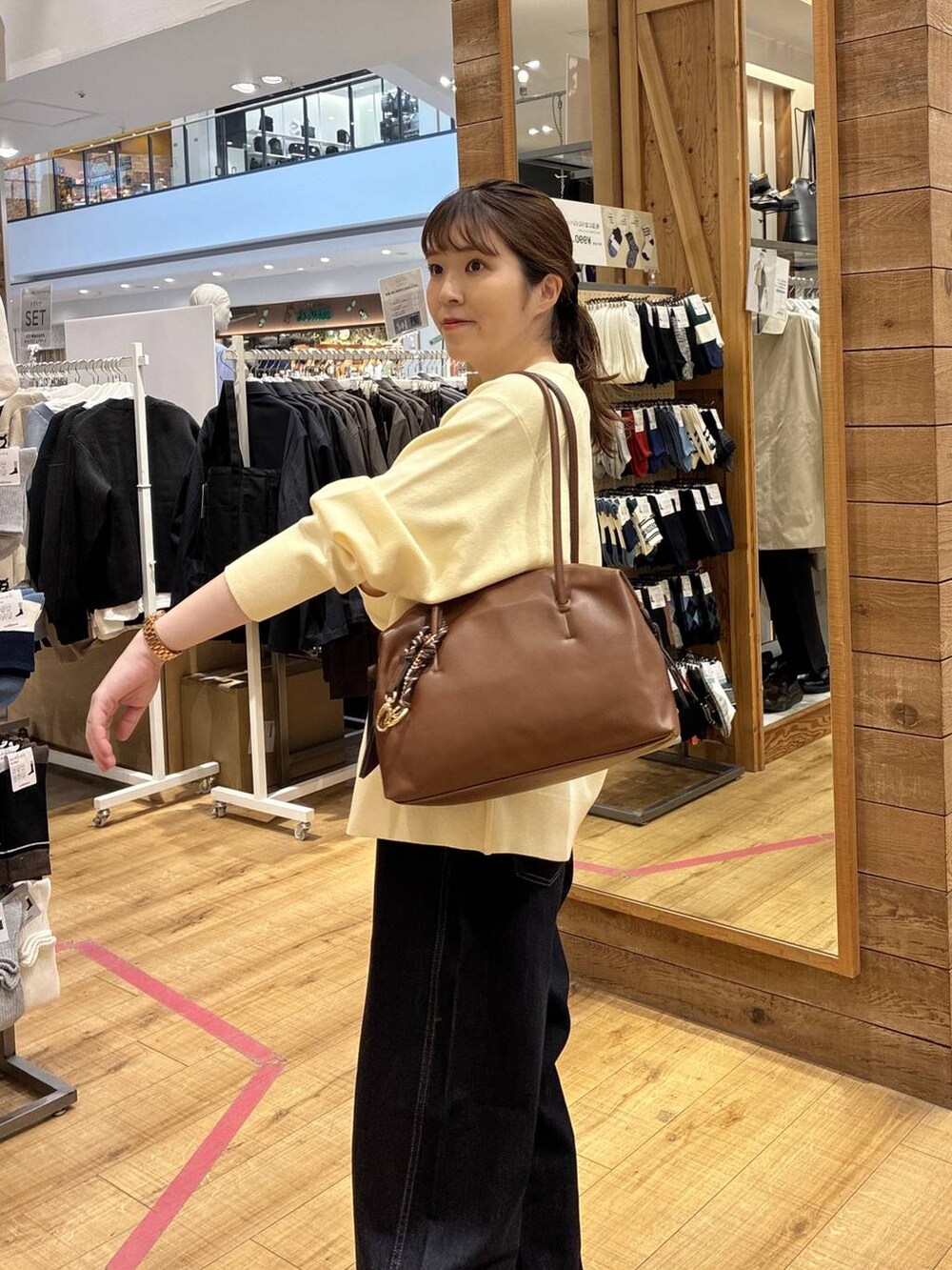 ブラウン系のボストンバッグ、ブルー系のデニムパンツ、イエロー系のカーディガン/ボレロを着用したレディースの春コーディネートの4枚目の写真