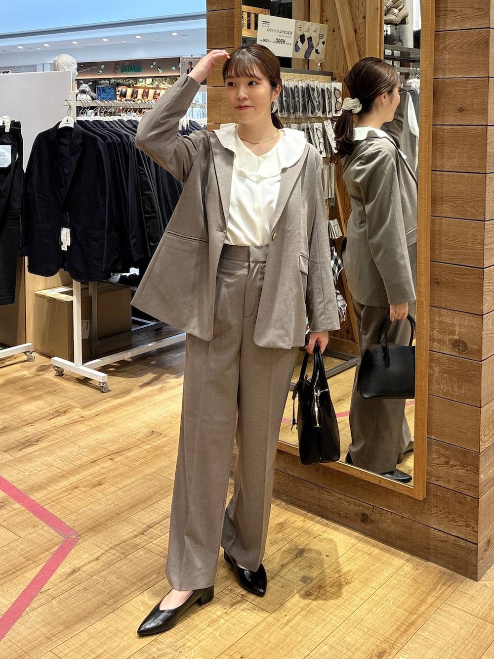 ブラック系のショルダーバッグ、ブラウン系のスラックス、ブラウン系のテーラードジャケットを着用したレディースの春コーディネートの2枚目の写真