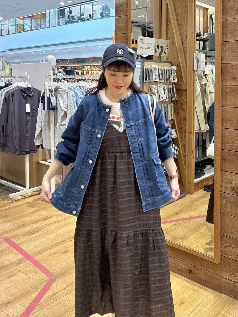 ベージュ系のショルダーバッグ、ブルー系のデニムジャケット、ブラウン系のワンピースを着用したレディースの春コーディネートの5枚目の写真