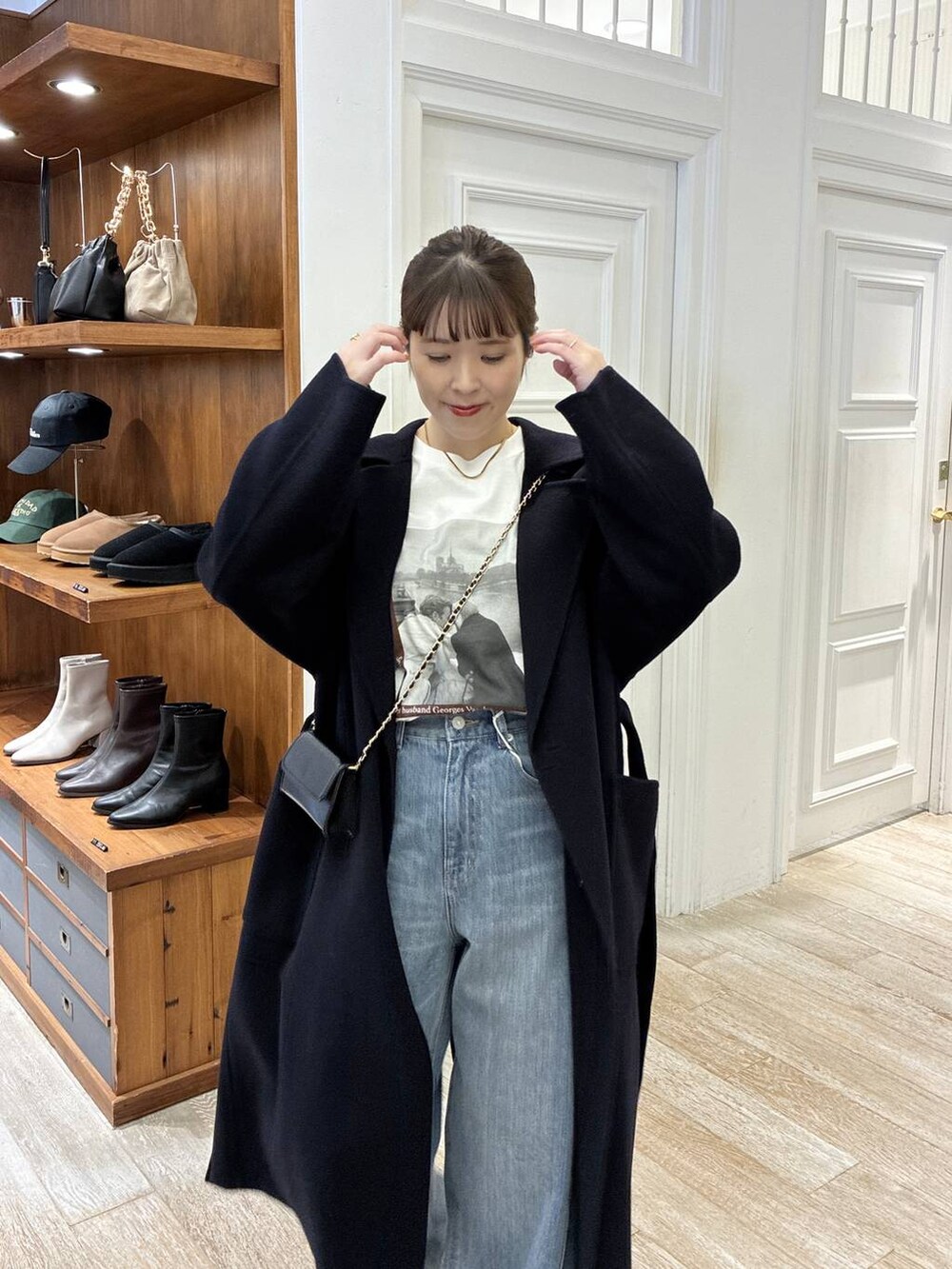 ブルー系のステンカラーコート、ブルー系のデニムパンツ、ホワイト系のTシャツ/カットソーを着用したレディースの秋コーディネートの4枚目の写真