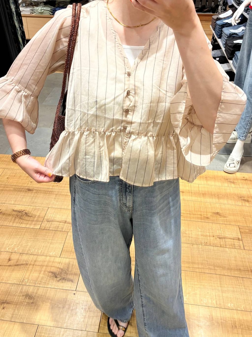 ブルー系のデニムパンツ、ホワイト系のタンクトップ、ブラウン系のトートバッグを着用したレディースの夏コーディネートの2枚目の写真