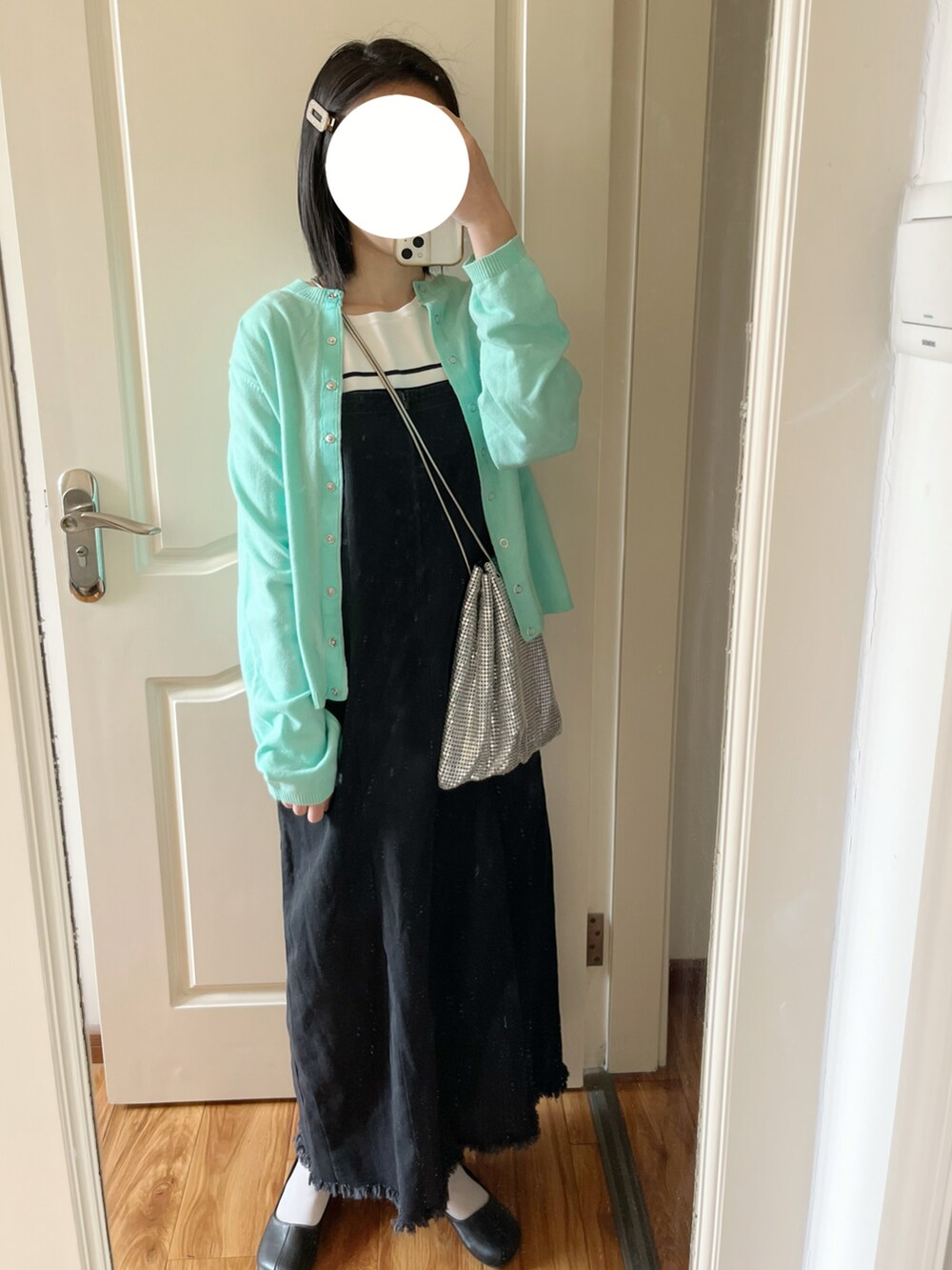 ブルー系のカーディガン/ボレロ、ブラック系のジャンパースカート、ブラック系のパンプスを着用したレディースの春コーディネートの2枚目の写真