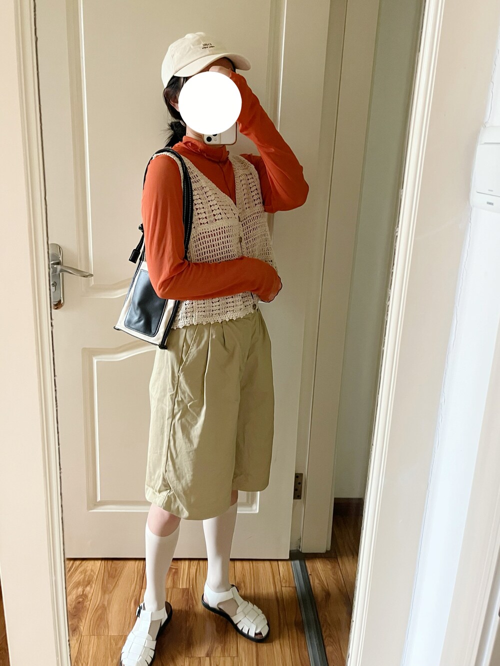 ブラック系のショルダーバッグ、オレンジ系のTシャツ/カットソー、ベージュ系のチノパンツを着用したレディースの春コーディネートの3枚目の写真