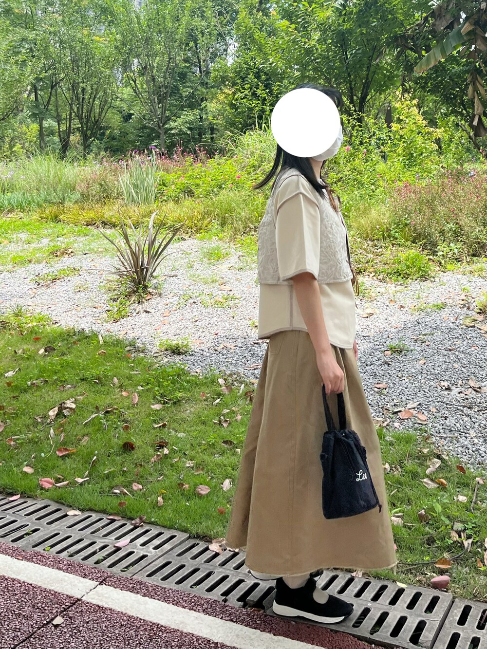 ホワイト系のベスト、ベージュ系のスカートを着用したレディースの春コーディネートの2枚目の写真