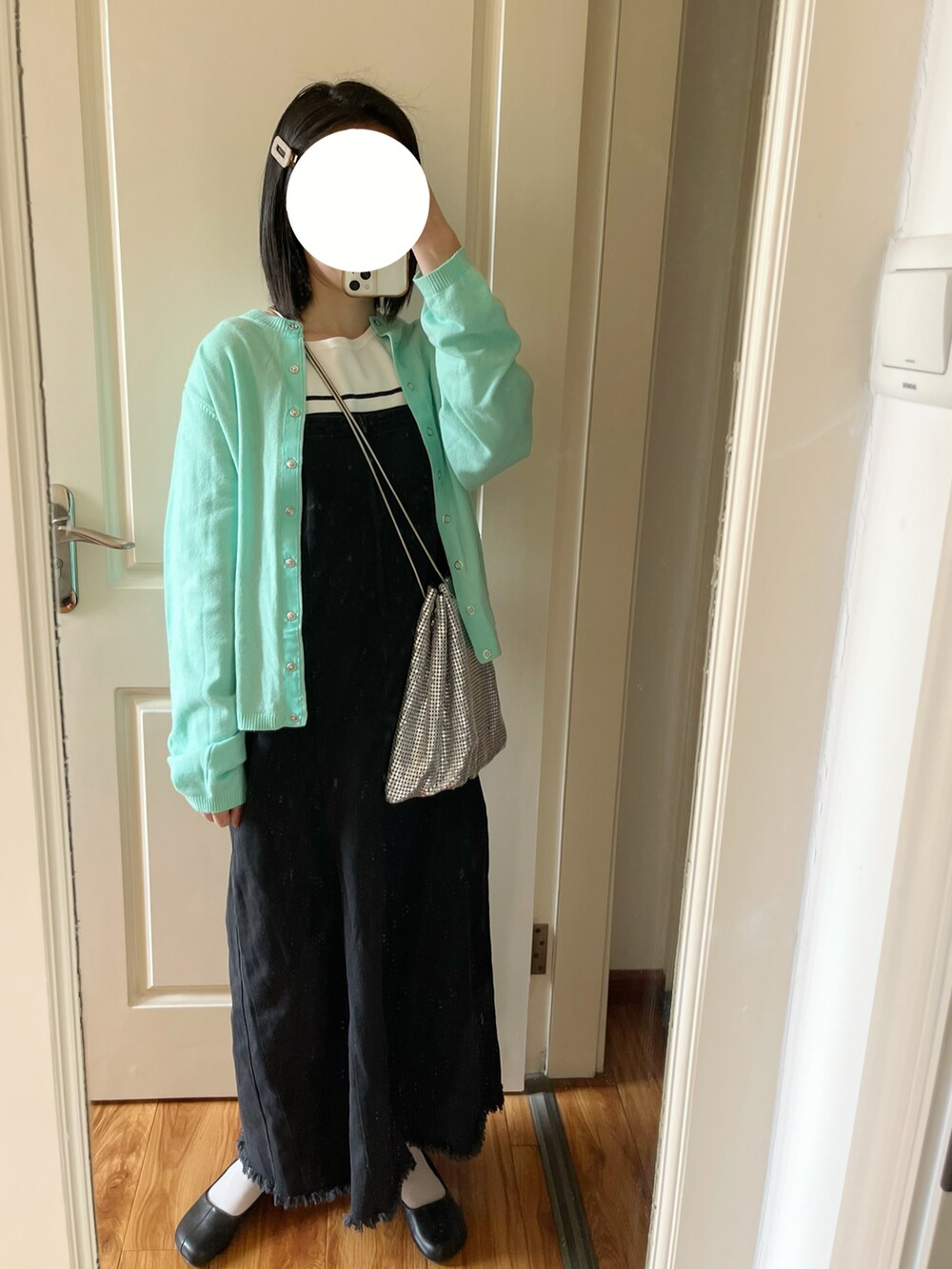 ブルー系のカーディガン/ボレロ、ブラック系のジャンパースカート、ブラック系のパンプスを着用したレディースの春コーディネートの3枚目の写真