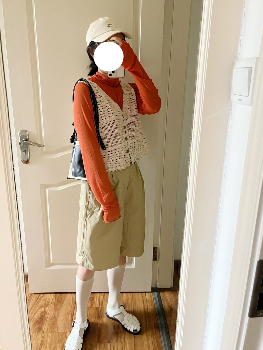 ブラック系のショルダーバッグ、オレンジ系のTシャツ/カットソー、ベージュ系のチノパンツを着用したレディースの春コーディネートの2枚目の写真